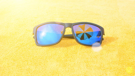 Sunglasses close up summer background. Beach pool equipment with travel sunglasses on yellow holiday towel. Outdoor relax holiday at oceanの写真素材