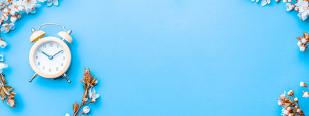spring blossom. May flowers and April floral nature with alarm clock on blue background. Branches of...