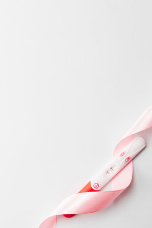 positive pregnancy test result. Woman pregnant test with pink silk ribbon on white background. Medical healthcare gynecological, pregnancy fertility maternity people conceptの写真素材