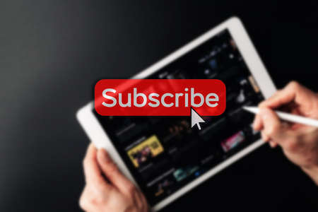 Subscription plan. Red online video subscribe button. Internet service on laptop digital tablet blurred technology background. Visual contents concept. social networking serviceの写真素材