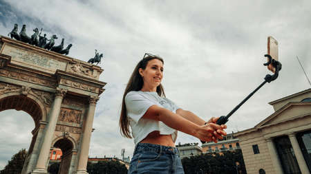 Travel influencers Milan island. Paint building house in Europe Milano. Photographer blogger girl with smartphone in Piazza del Duomo, Cathedral Square. Traveling and freelancing, modern lifestyleの写真素材