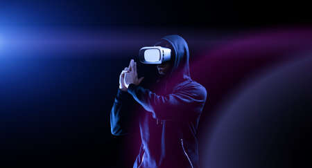 virtual reality glass vr. Young man in digital glasses for 3d virtual reality game on dark background. Augmented reality, game, future technology concept. VRの写真素材