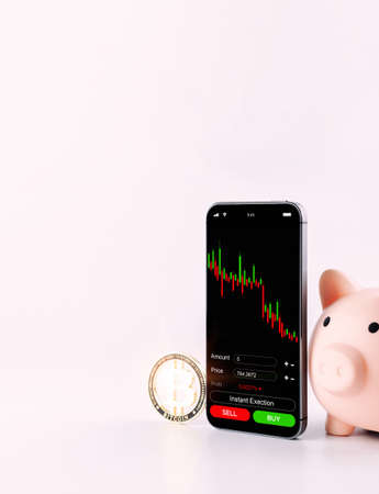 Cryptocurrency exchange. Pink pig bank, gold crypto currency BTC bitcoin on white background. bitcoin trading mobile phone app. Save money investment and business financeの写真素材