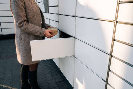 Delivery locker. Post automat terminal and hands with parcel courier box. Online purchase delivery service concept.の写真素材