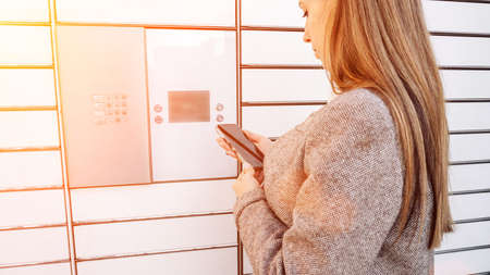 post locker. Delivery automat terminal and hands with parcel courier box. Parcel delivery, pickup point with lockers, hand with parcel, contactless pack deliveryの写真素材