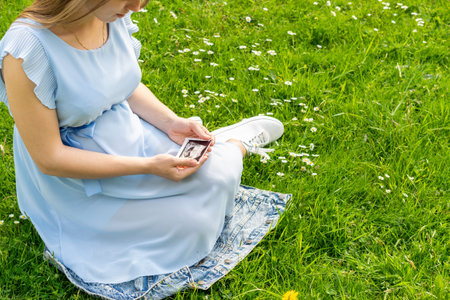 Ultrasound image pregnant baby photo. Woman holding ultrasound pregnancy picture on grass flower background. Pregnancy, medicine, pharmaceuticals, health care and people conceptの写真素材