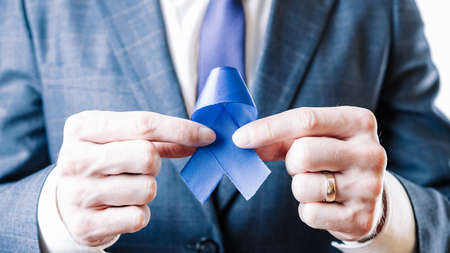 cancer people prostate. Business man with blue ribbon in hands on white background. Awareness prostate cancer of men health in November. Man Healthcare and World cancer day conceptの写真素材