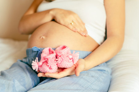 Children shoes pregnancy woman. Beautiful pregnant woman holding pink baby shoes. Waiting for baby....