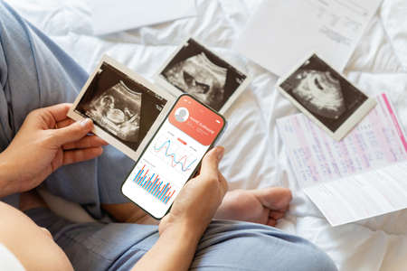 Pregnancy smartphone app. Pregnant woman holding smartphone. Mobile pregnancy online maternity application. Concept maternity, pregnancy, childbirth.の写真素材