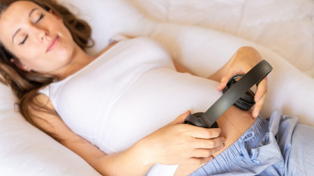 Pregnant woman music listen. Cheerful pregnancy girl relaxing listening music in headphones. Mother...