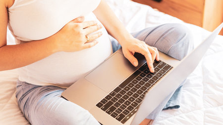 Pregnancy app laptop. Mobile pregnancy online maternity notebook application. Pregnant mother using digital computer. Concept of pregnancy, maternity, expectation for baby birthの写真素材