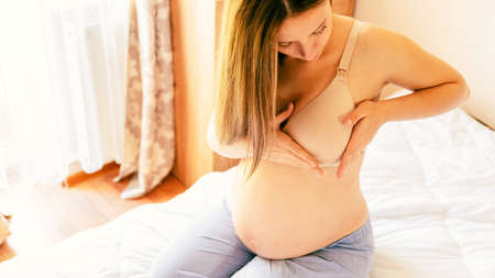 Breast examination cancer pregnant woman check. Young pregnancy woman examining breast for signs lumps. Breast self exam BSE, breast cancer awareness conceptの写真素材
