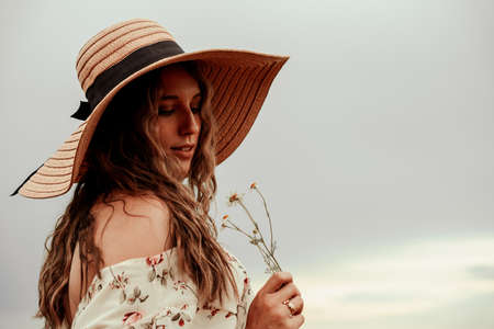 Woman wheat field nature. Happy young woman in sun hat in summer wheat field at sunset. Copy space, sunset, flare light, summer season. Boho chic styleの写真素材