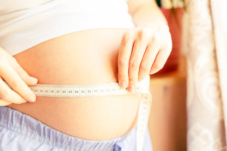 Pregnant belly woman measure. Happy beautiful pregnant woman with tape measuring belly. Pregnancy, medical health care conceptの写真素材