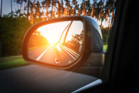 road trip car mirror. Sun, highway car road reflection in mirror. summer holidays trip conceptの写真素材