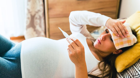 Pregnancy flu thermometer. Pregnant woman holding thermometer, check fever flu temperature. Pregnancy girl sick. Therapy, healthcare, motherhood conceptの写真素材