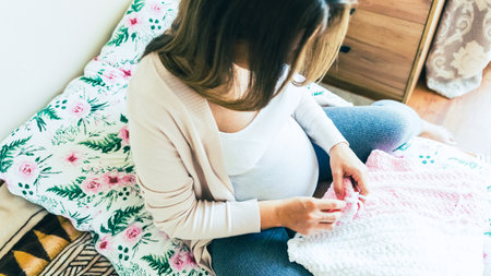 Pregnant mother crochet kid cloth. Cute pregnancy woman knit fashion winter baby girl clothes. Cozy knitting womanの写真素材