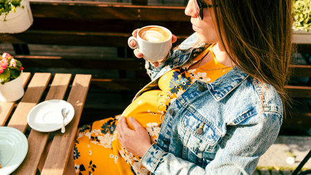 Happy pregnancy girl drink hot coffee in restaurant. Represent breakfast for energy and freshness conceptの写真素材