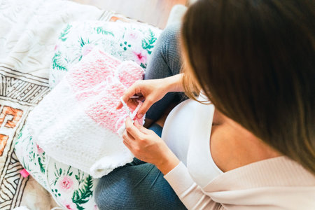 Woman knitting baby winter clothes. Cute pregnant woman knit fashion winter baby girl clothes....
