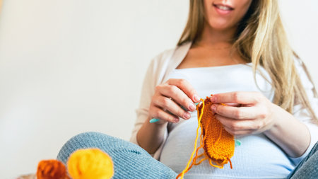 Pregnancy knitting baby winter clothes. Pregnancy mother crochet kid cloth. Cute pregnant woman knit fashion winter baby girl clothes. Warm winter cozy clothes for babyの写真素材