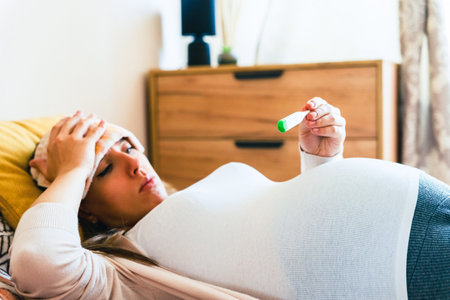 Pregnancy fever temperature check. Pregnant woman holding thermometer, check fever flu temperature. Pregnancy girl sick. Concept maternity, pregnant, childbirthの写真素材