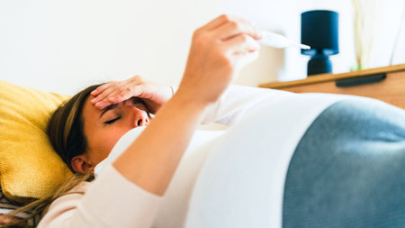 Pregnant fever check. Pregnancy woman holding thermometer, check fever flu temperature. Pregnant girl sick. Concept of pregnancy, maternity, expectation for baby birthの写真素材