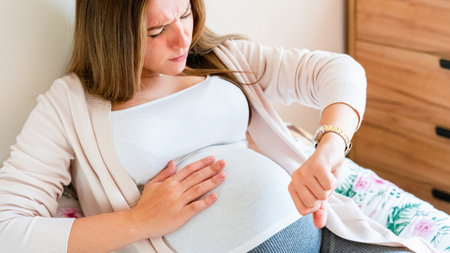 Pregnant time go hospital. Pregnant holding baby belly, woman watching clock. Childbirth time, contractions pain. Concept maternity, pregnant, childbirthの写真素材
