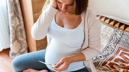 Pregnancy health temperature check. Pregnant woman holding thermometer, check fever flu temperature. Pregnancy girl sick. Concept maternity, pregnant, childbirthの写真素材