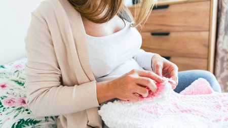 Knitting socks pregnancy woman. Pregnant mother crochet kid cloth. Cute pregnancy woman knit fashion winter baby girl clothes. Cozy knitting womanの写真素材