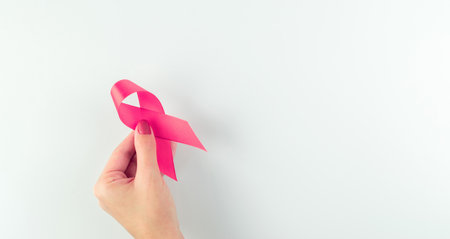 Cancer awareness. Health care symbol pink ribbon in woman hands on white background. Breast woman support concept. World cancer dayの写真素材