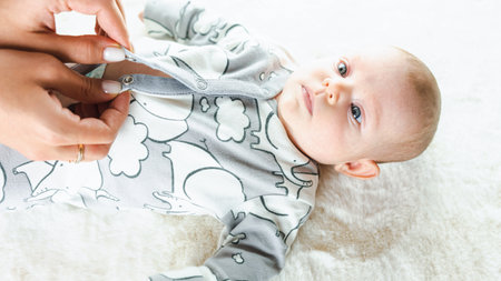 baby cute baby banner. Happy cute baby kid girl lying on white bed background. light background. little child. serious emotionの写真素材