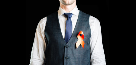Hiv aids. Red ribbon in hiv world day isolated on dark background. Man holding awareness aids and cancer symbol. Health, Medical sign. copy space.の写真素材