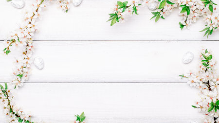 Easter flat. Cherry tree blossom, white happy easter eggs on wood spring background. Springtime concept.の写真素材