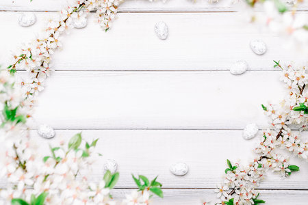 Easter eggs background. May flowers, white happy easter egg on wooden spring background. Easter card. Flat lay.の写真素材