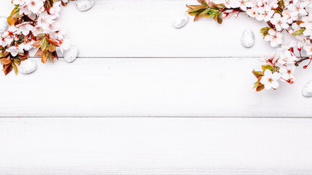 Easter white background. Spring flower border, white happy easter egg on wooden spring background. Easter card. Flat lay.の写真素材
