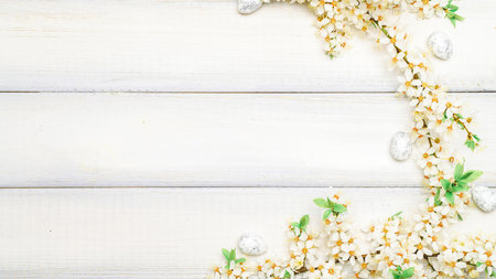 Easter white background. Spring flower border, white happy easter egg on wooden spring background. Easter card. Flat lay.の写真素材