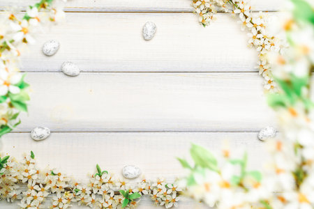 Easter white background. Spring flower border, white happy easter egg on wooden spring background. Easter card. Flat lay.の写真素材