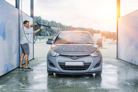 Man cleaning car. Spray hose foam soap. Car wash water shine exterior.の写真素材