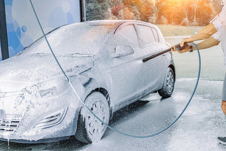 Man cleaning car. Spray hose foam soap. Car wash water shine exteriorの写真素材