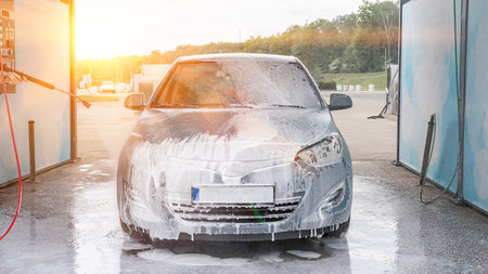 Man cleaning car. Spray hose foam soap. Car wash water shine exteriorの写真素材