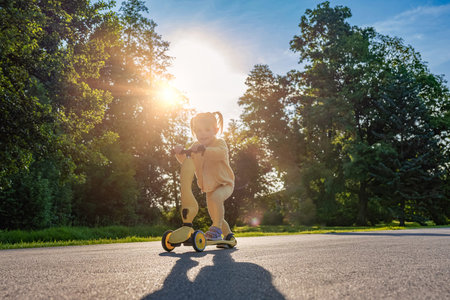 Child scooter riding. Girl yellow scooter park. Motion day lifestyle travel.の写真素材