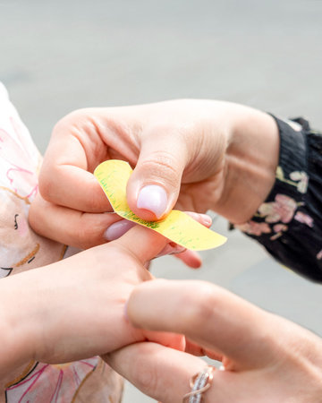 Close-up of female hands cutting a yellow paper.