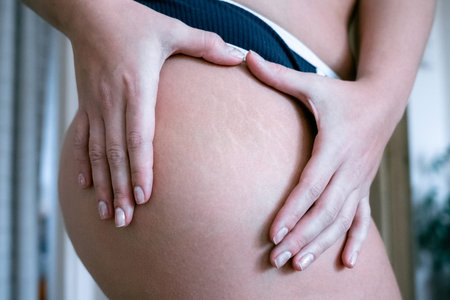 Closeup of female hands on the buttocks of a pregnant woman.