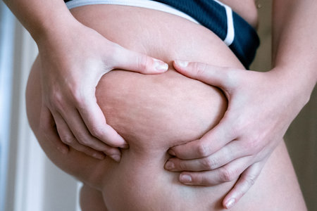 Woman weight awareness. Female checking abdominal area indoors.