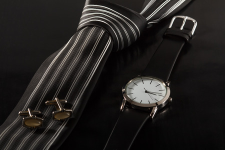 Silk tie, cufflinks, watch with a leather strap on a black backgroundの写真素材