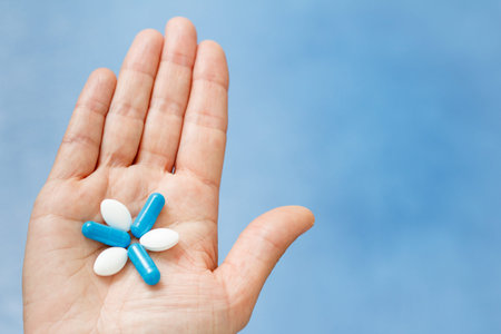 Close-up shot of hand holding blue and white pills in the form like flower. Pills on woman hand