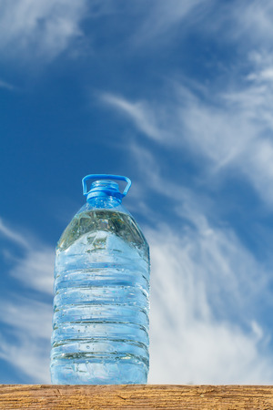 Big water bottle on wooden board with blue sky on background. Fresh healthy backgroundの写真素材