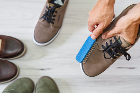 Man cleaning and polishing leather shoes with brush on wooden background