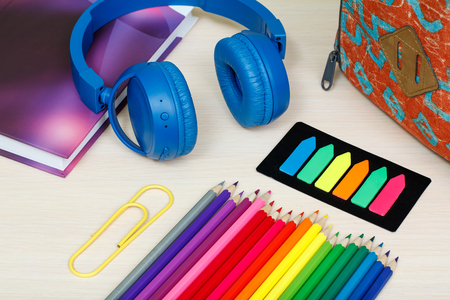 School supplies. School backpack, book, color pencils, paper clip, color bookmarks and headphones on wooden table. Top view. Back to school concept.の写真素材