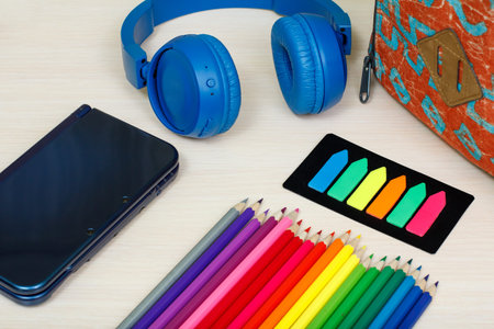 School supplies. School backpack, book, color pencils, ebook, color bookmarks and headphones on...